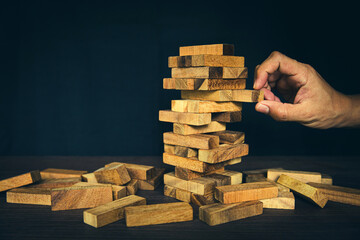 Close-up hand prevents and choose wooden block not falling concepts of financial risk management...