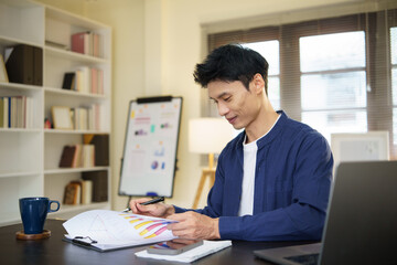 Focused businessman analyzing financial charts and documents at his desk.