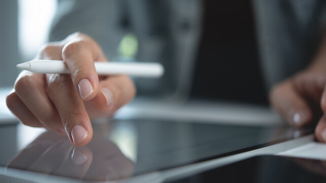 Business woman using digital tablet, finger touching on screen, reading e-document, proofreading before signing with stylus pen via mobile app, closeup. working on computer at office