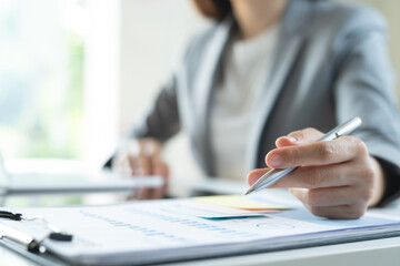 Closeup, businesswoman working at office. Business woman analyzing financial report with business document on table, marketing research and planning