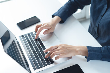Close up, business woman hand typing, working on laptop computer with digital tablet and smartphone on office table, surfing the internet, searching the information, business technology, remote work