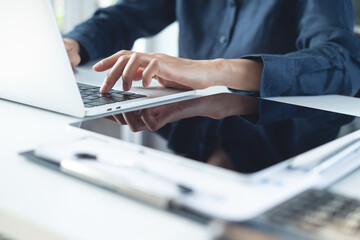 Business woman working on laptop computer with digital tablet and financial report on table office. Businesswoman surfing the internet via laptop, online working, business technology, close up