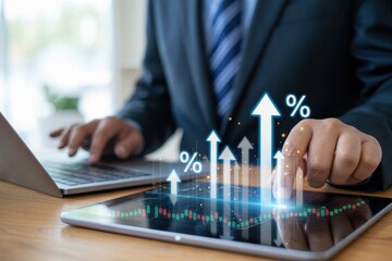 Businessperson interacting with digital financial charts on a tablet and laptop.
