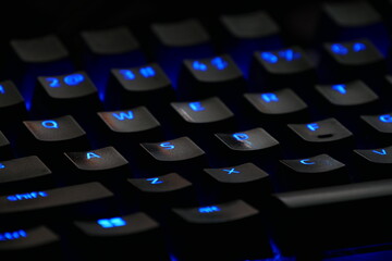 Close-up of illuminated mechanical keyboard keys with blue backlighting, showcasing technology and gaming equipment details for digital workspaces and gaming setups