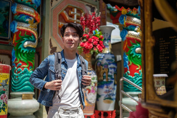Traveler in denim jacket exploring a traditional religious shrine during a cultural trip.