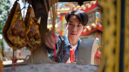Fototapeta premium Young male traveler offering incense at a traditional Chinese temple.
