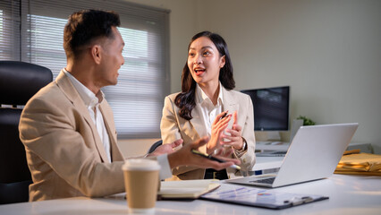 Fototapeta premium Two coworkers collaborating on a project discussing strategy in modern office.