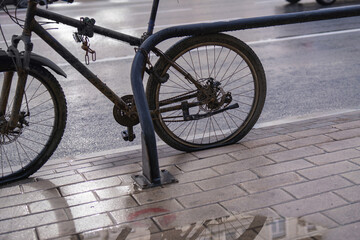 Obraz premium Abandoned high-end tuned sports bicycle, rusted and dirty with flat tires, chained to a pipe at a bike rack