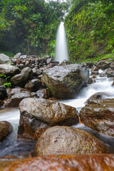 A serene waterfall cascades over rocks in a lush, green forest setting.