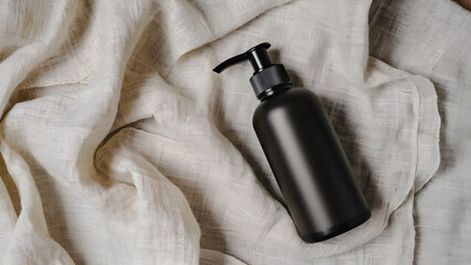 Black pump dispenser bottle on beige wrinkled fabric