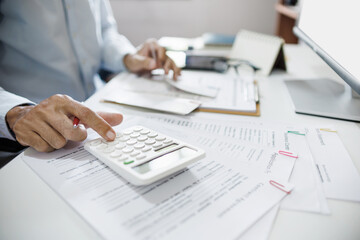 Accountants working in office use calculators to calculate business costs, profits and tax