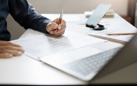 hand of businessman reviewing document at office. legal expert, professional lawyer working with computer reading and checking financial documents and business contract
