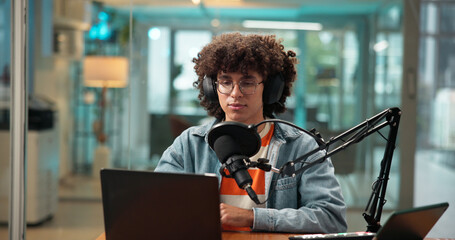 Man, laptop and headphones with mic in studio, recording podcast and sound check for broadcast....