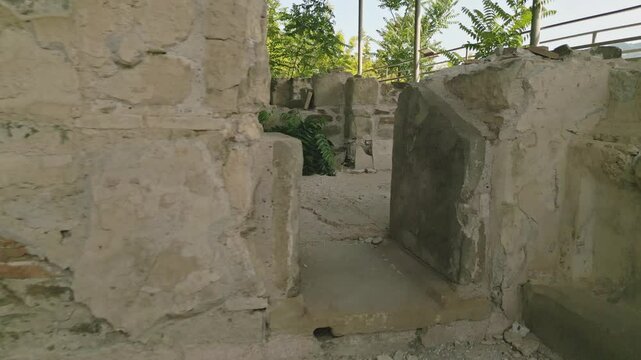 Walking point of view through Preserved remains of the ancient royal bath structure at Armaziskhevi site, surrounded by greenery under protective roof in Mtskheta region, Georgia