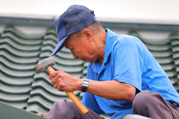 屋根を修理するおじさん
