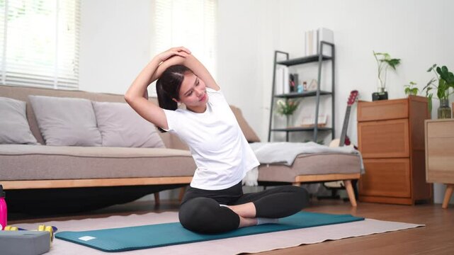 Young female doing shoulder stretch yoga exercise at home for body fitness and stress relief