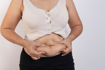 Overweight woman hand pinching excessive belly fat on gray background, Healthy concept
