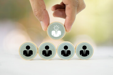 Hand chooses wooden toy stack with person icons for HR human resources or personal leader training...
