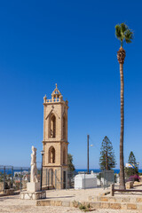 Ayia Napa, Cyprus – June 6, 2025: History centre, monastery tower with palm tree