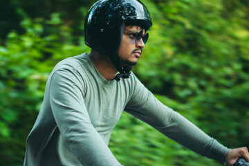 Closeup of young guy enjoying motorbike ride in the forest.