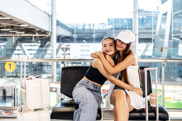 Young asian girl happily hugging her female friend together, with luggage, and are excited from their joint flight to the vacation or studying,  Air travel, summer holiday