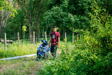 View of a young man walking in the park with his bike in the countryside.