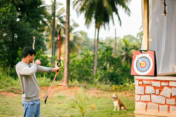 Young Indian man enjoying archery practice in the park.