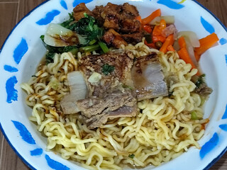 Guring beef noodle soup, equipped with delicious toppings, served on a traditional Indonesian iron plate.