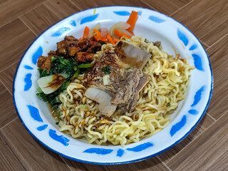Guring beef noodle soup, equipped with delicious toppings, served on a traditional Indonesian iron plate.