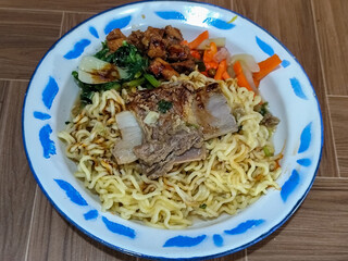 Guring beef noodle soup, equipped with delicious toppings, served on a traditional Indonesian iron plate.