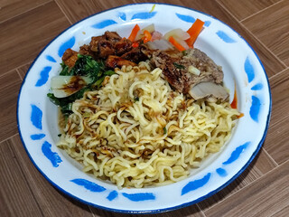 Guring beef noodle soup, equipped with delicious toppings, served on a traditional Indonesian iron plate.