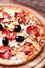 Pizza with salami and mozzarella cheese. Wooden background. Soft focus. Close up.	