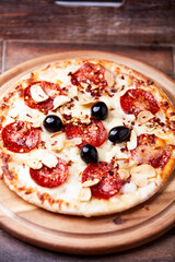 Pizza with salami and mozzarella cheese. Wooden background. Soft focus. Close up.	