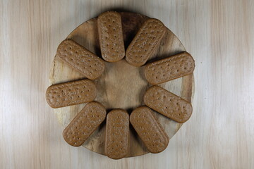 Close up of chocolate biscuits on a round wooden chopping board.