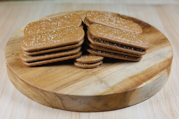 Close up of chocolate biscuits on a round wooden chopping board.
