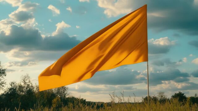 A bright yellow flag waving in a green field, perfect for outdoor activities or to represent a warning sign