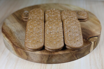 Close up of chocolate biscuits on a round wooden chopping board.