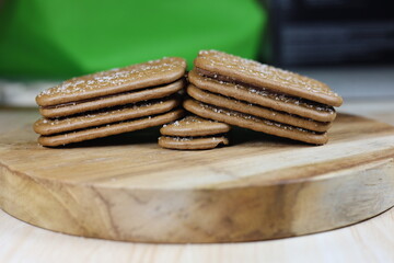 Close up of chocolate biscuits on a round wooden chopping board.