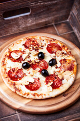 Pizza with salami and mozzarella cheese. Wooden background. Soft focus. Close up.	