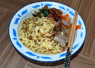 Guring beef noodle soup, equipped with delicious toppings, served on a traditional Indonesian iron plate.