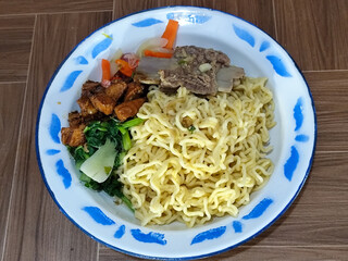 Guring beef noodle soup, equipped with delicious toppings, served on a traditional Indonesian iron plate.