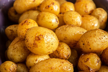 Baked baby potatoes with spices in baking dish closeup