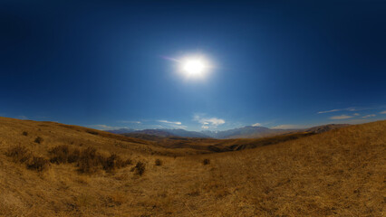 Dry, open landscape with rolling hills under a bright sun.