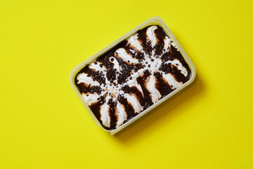Zenith view.. Stracciatella ice cream in a container. Copy space and yellow background. 