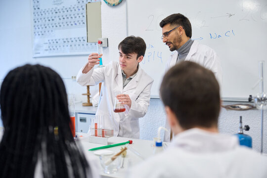 Chemistry students and teacher performing experiment in laboratory