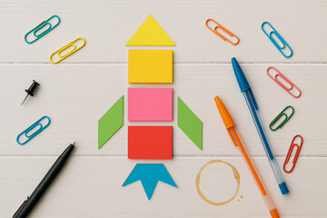 Colorful Paper Rocket Craft with Pens and Paperclips on White Wooden Background