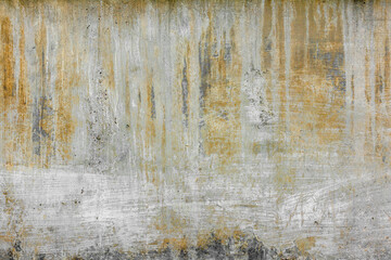 rough concrete wall with old white paint strokes yellow streaks and stains