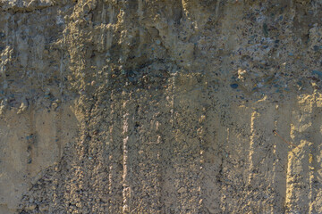 Weathered Cheap Uneven Concrete Surface with Pebbles under tangential harsh light