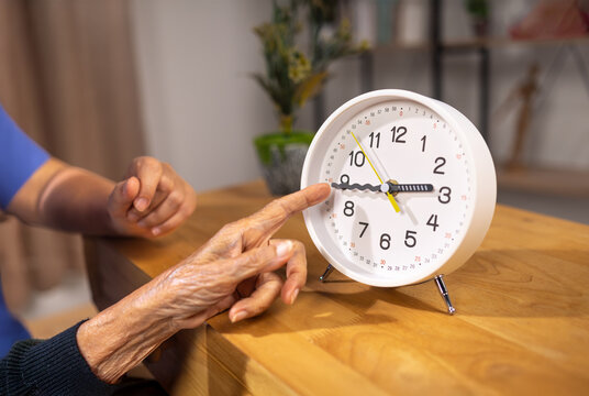 Asian Elderly Woman with Dementia Practicing Read Time on Clock.