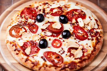 Pizza with salami and mozzarella cheese, jalapeno pepper and black olives. Wooden background. Soft focus. Close up.	